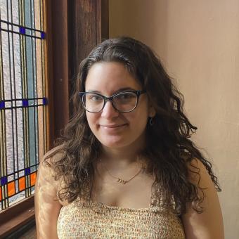 woman with brown hair standing by window
