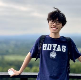 man in blue HOYAS shirt standing in front of railing