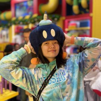 Woman in tye dye shirt wearing a blue plush hat